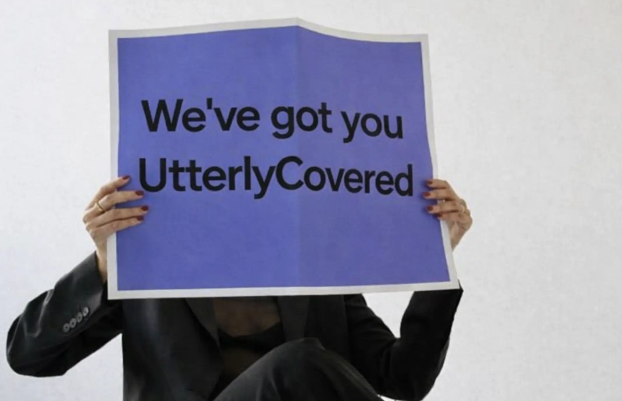 Person holding UtterlyCovered sign representing comprehensive life insurance coverage and protection for UK families