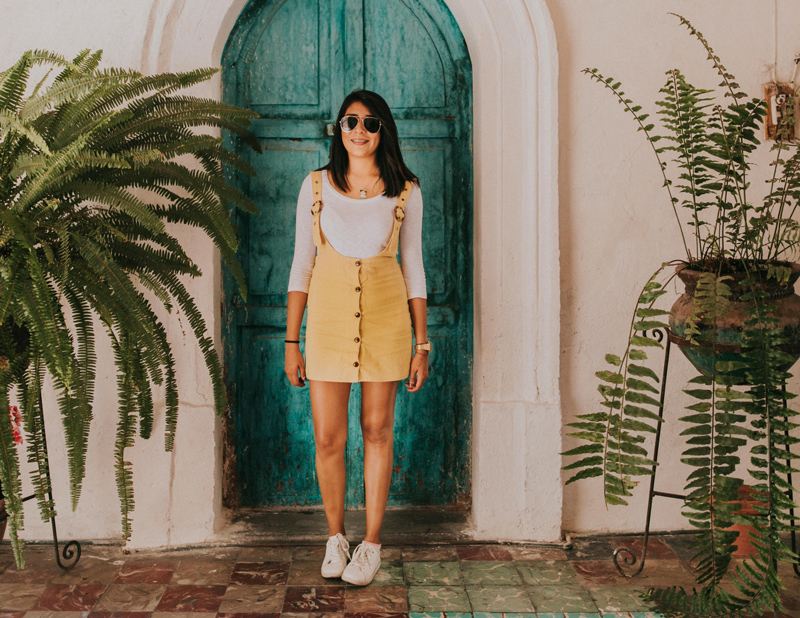 Woman standing in front of beautiful home entrance with greenery, representing home insurance coverage