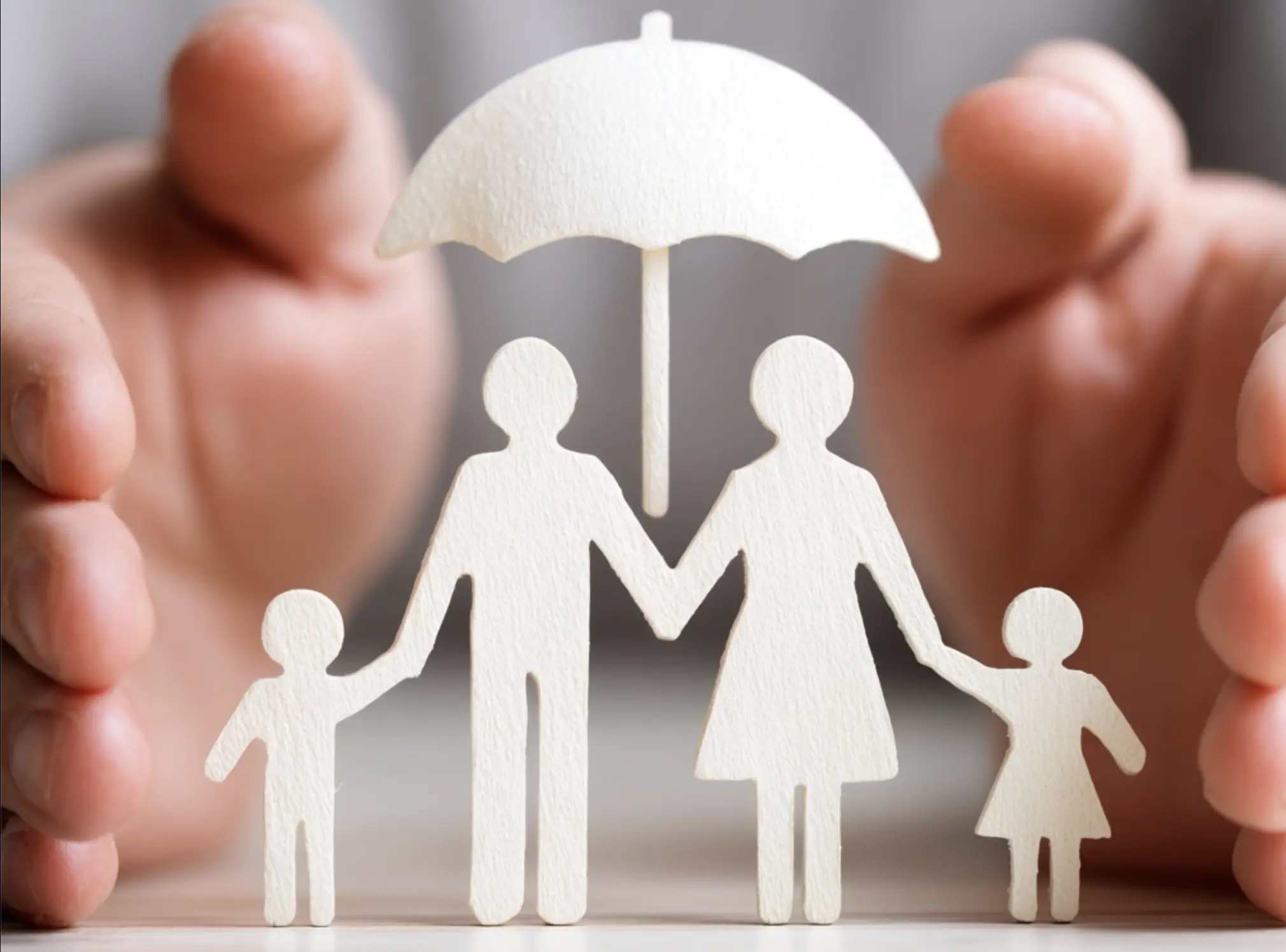 Hands protecting paper family under umbrella representing comprehensive life insurance coverage UK