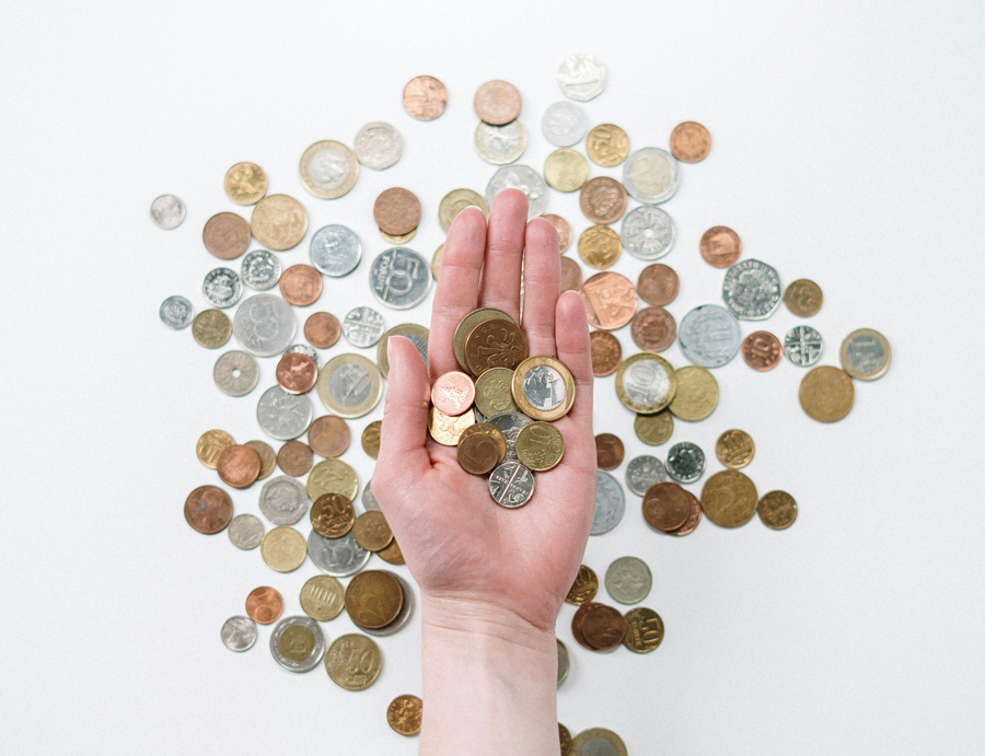 Hand holding coins with scattered coins background representing money-saving insurance tips